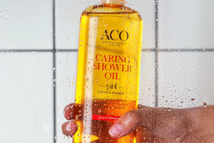 ACO Caring Shower Oil flaska i duschen med vattenstänk och hand
