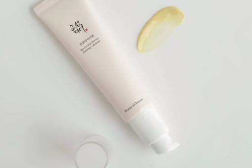 Närbild på Beauty of Joseon Revive Eye Serum-tub och en klick av det gula serumet på en ljus yta.