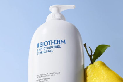 Biotherm Lait Corporel Body Milk pumpflaska med en färsk citron på blå bakgrund