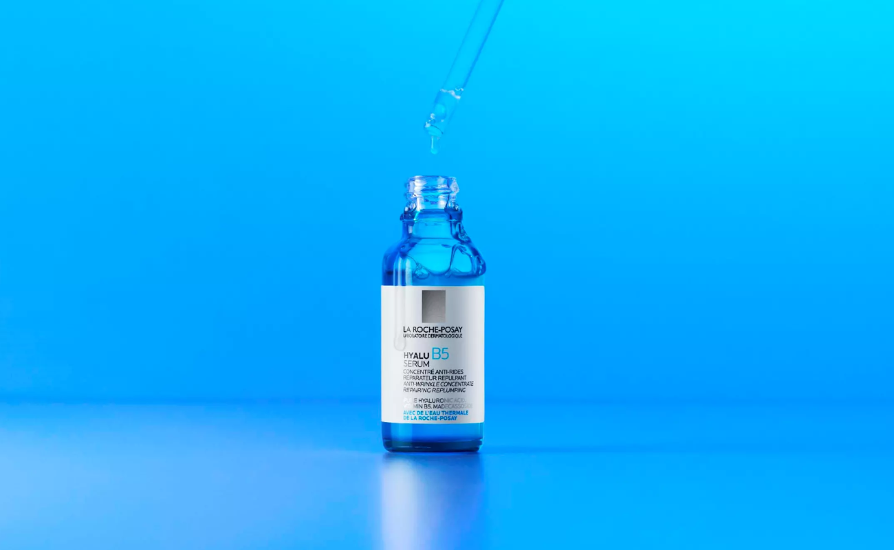 Närbild på La Roche-Posay Hyalu B5 Serum i blå glasflaska med pipett mot en klarblå bakgrund.