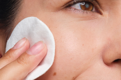 Närbild på applicering av ansiktsvatten med bomullsrondell på kinden för exfoliering.